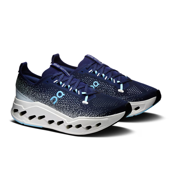 On running shoe in navy blue with a speckled pattern, a light blue On logo, and a white sculpted sole with black cutouts, shown against a plain white background.