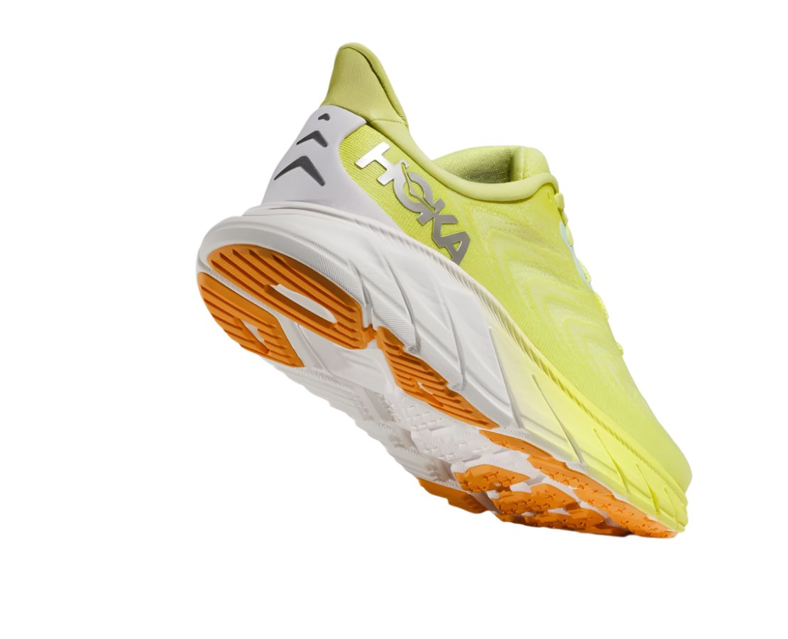 Back angle view of the Women's Arahi 6 by HOKA in the color Citrus Glow/White