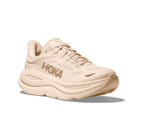 A deeper tan Hoka decal is in the middle on the lateral side of the upper.