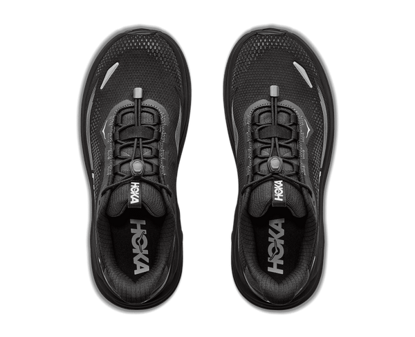 A pair of black HOKA running shoes shown from a top-down view against a solid green background.