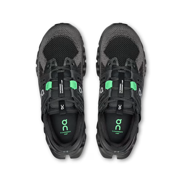 A pair of black and dark gray running shoes with bright green accents, shown from a top-down view on a white background. The brand 'On' is clearly visible on the straps and the insole.