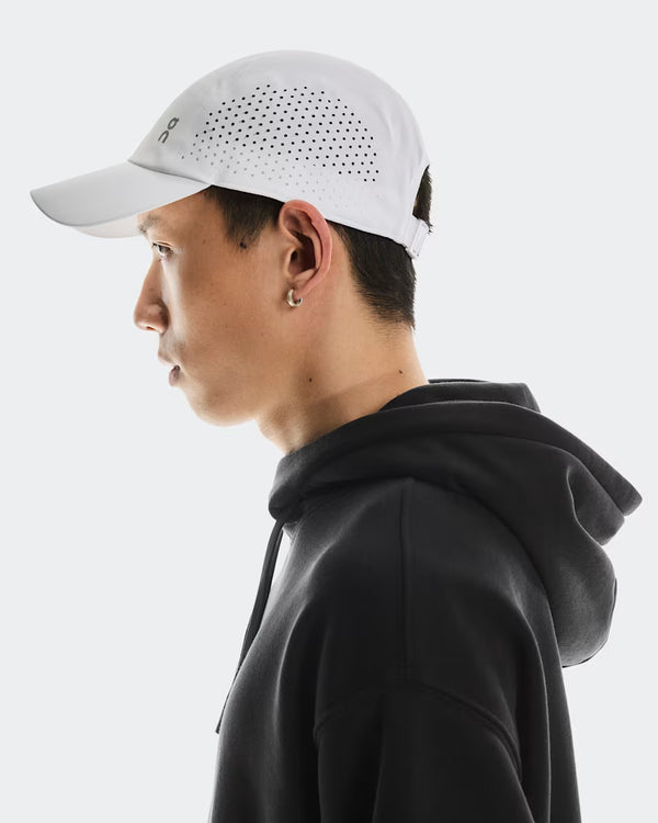 Person wearing a white cap and black hoodie on a light gray background