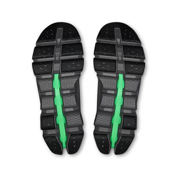 The oustole of a pair of black athletic shoes shown from the sole view, featuring a bright green vertical strap detail on each side, set against a plain white background.