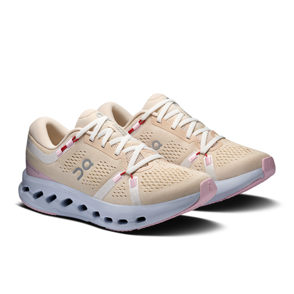 Pair of beige running shoes with white soles on a white background