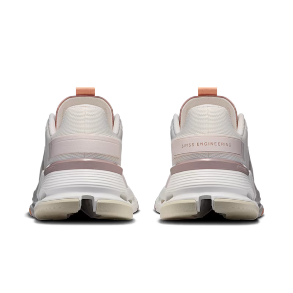 Rear view of a pair of white athletic sneakers with dusty pink accents and a peach pull tab, featuring 'SWISS ENGINEERING' text on the heel.