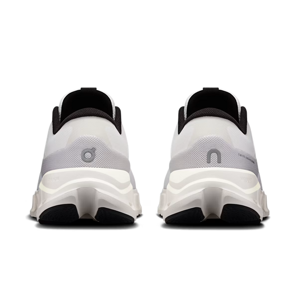 A pair of white and black chunky sneakers shown from the back, featuring a thick sculpted sole, black collar lining, and a gray logo on the heel.