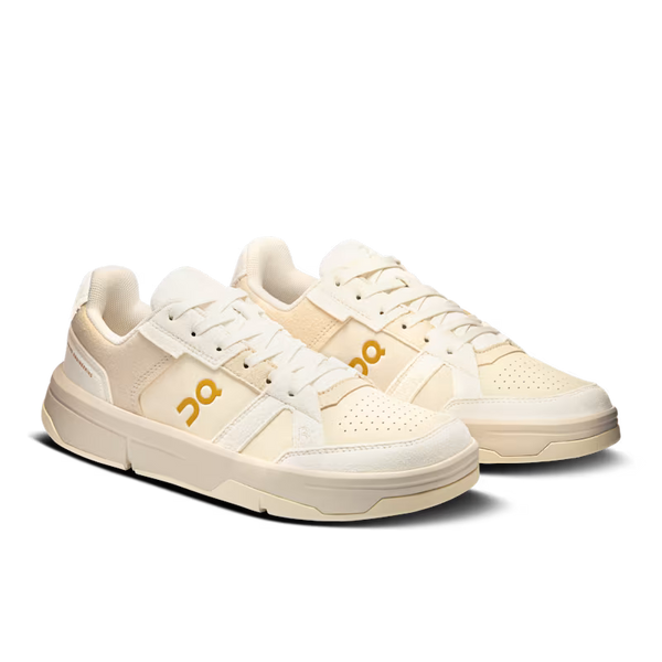 Pair of cream-colored sneakers with a logo on a white background