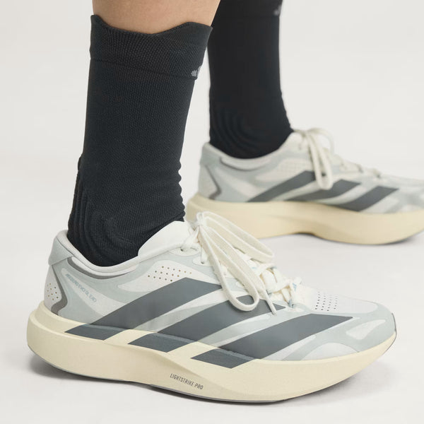 A person wearing adidas running shoes with black socks.