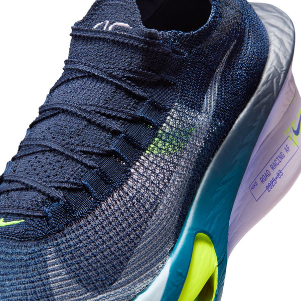 Close-up of a blue athletic shoe with green accents on a white background.