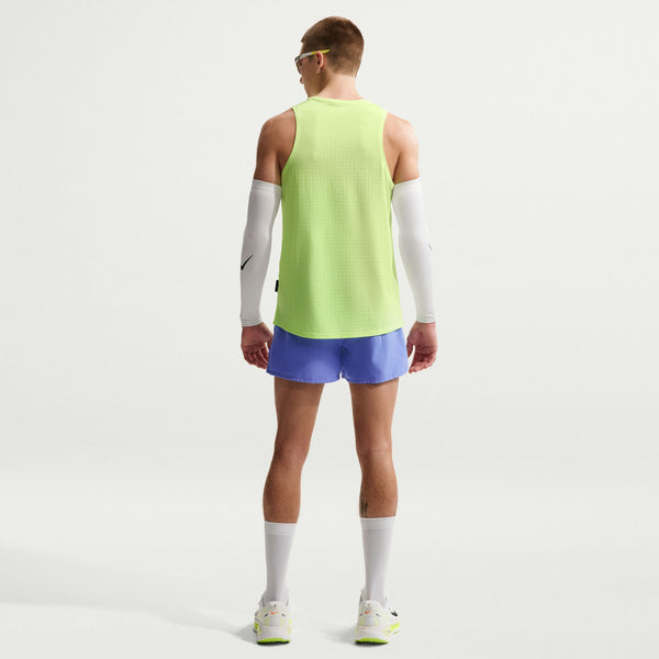 Person wearing a bright green sleeveless shirt and blue shorts on a white background