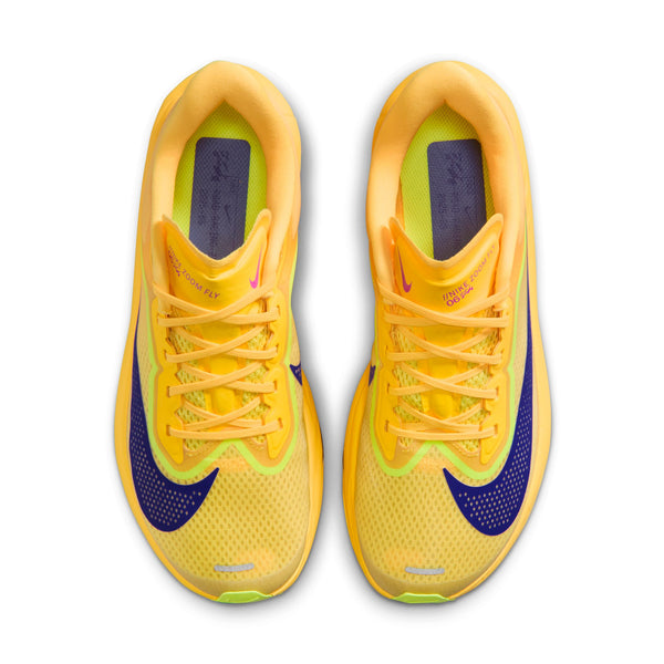 Top down look at a pair of yellow and purple running shoes on a white background.