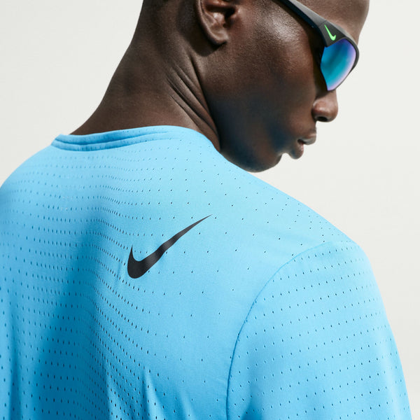 Person wearing a blue Nike shirt with a black logo on a neutral background