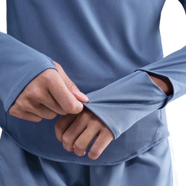 Person wearing a blue long-sleeve shirt with sleeves rolled up, on a white background