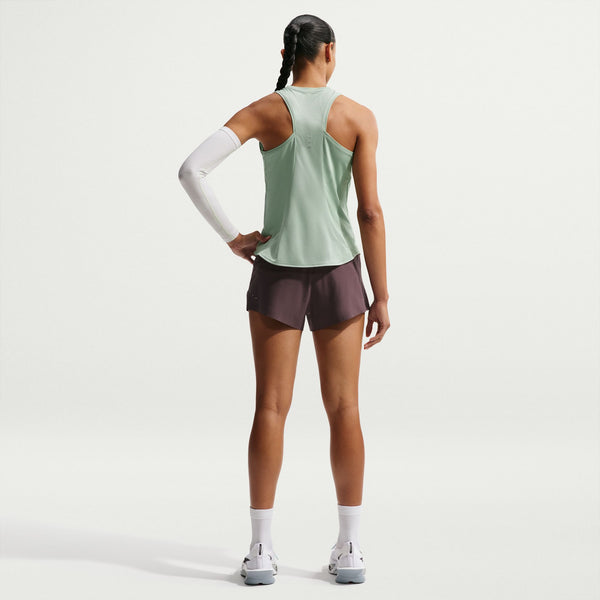 Person wearing a light green tank top and dark shorts on a white background