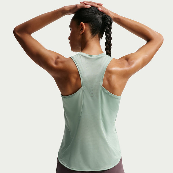 Woman wearing a light green tank top with a plain background