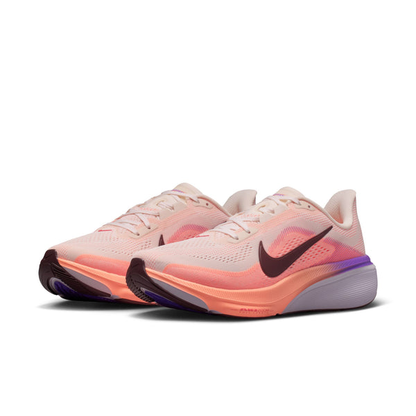 Pair of women's light pink and orange running shoes with a Nike logo on a white background