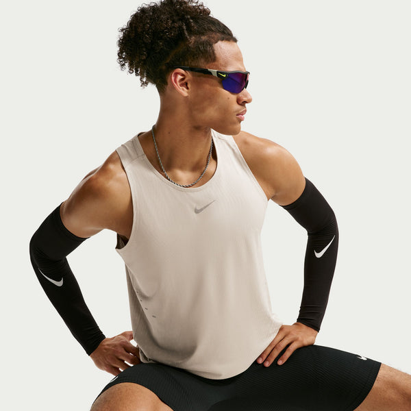 Person wearing a beige tank top and black shorts with Nike branding, on a plain background