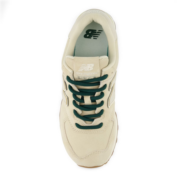 A New Balance sneaker in cream suede and leather with dark green laces, shown from on a white background.