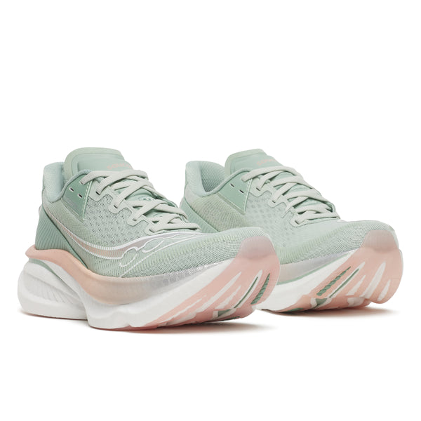 Pair of light green running shoes with pink soles on a white background