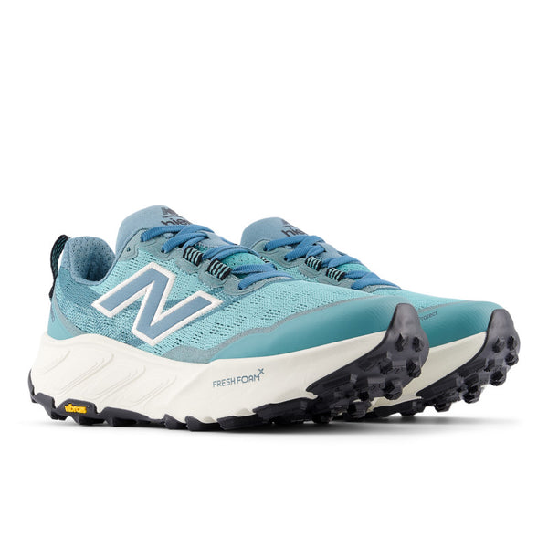 A paior of new balance light teal running shoe with white sole on a white background.