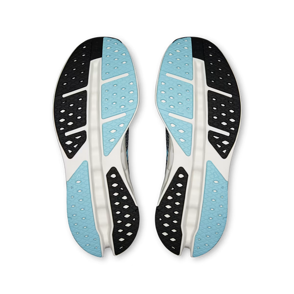 On running shoe in navy blue with a speckled pattern, a light blue On logo, and a white sculpted sole with black cutouts, shown against a plain white background.