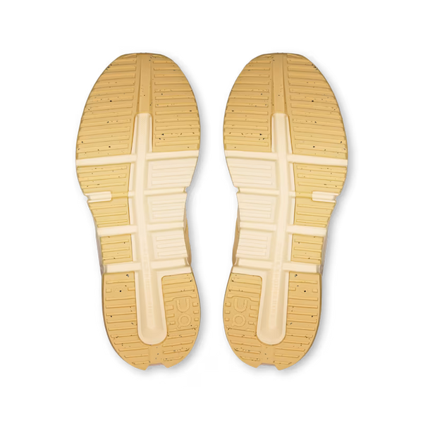 A pair of shoe soles viewed from above, showing a tan rubber outsole with a cream-colored central crossbar and tread pattern, set against a plain white background.
