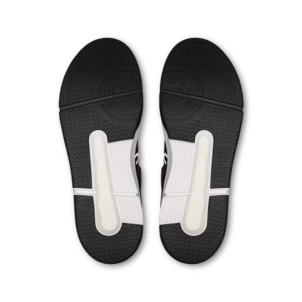 Top-down view of a pair of athletic shoe soles, showing a black textured outsole with white heel inserts on a plain white background.