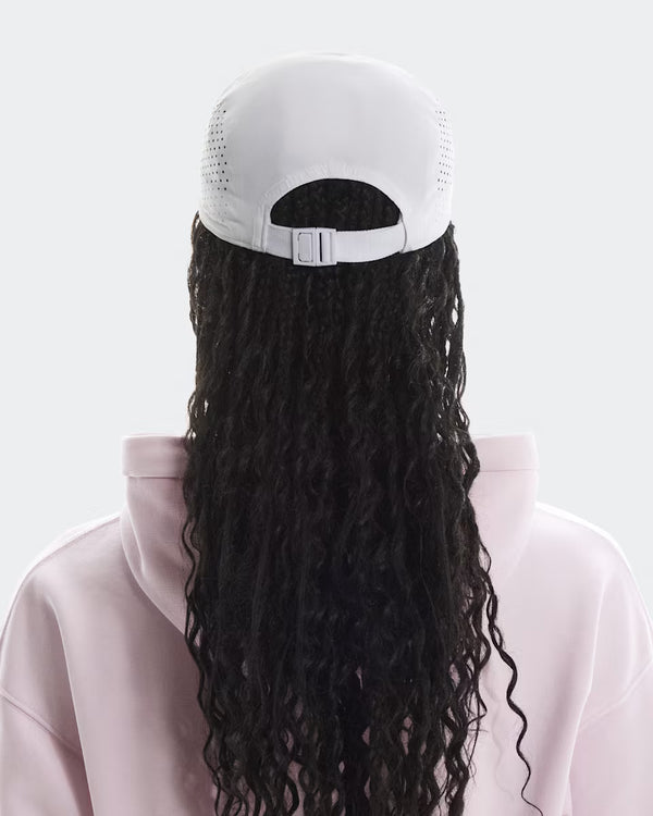 Person wearing a white cap with a long black braided ponytail on a light gray background