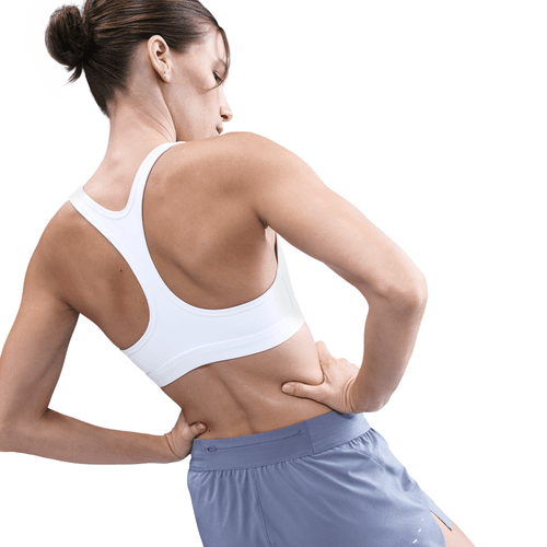 Woman wearing a white sports bra and blue shorts on a white background