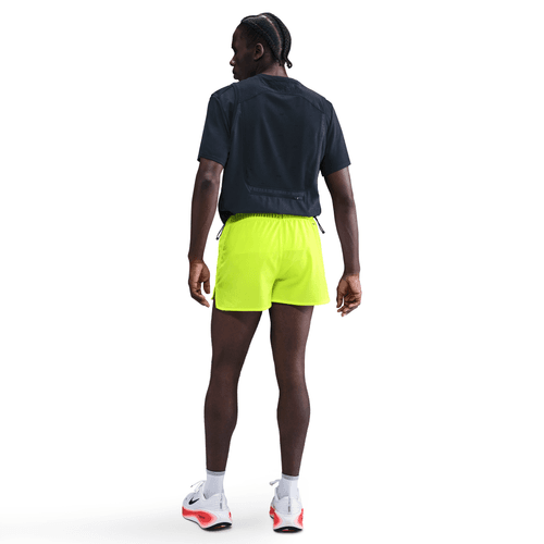 Person wearing a navy shirt and bright yellow shorts on a white background