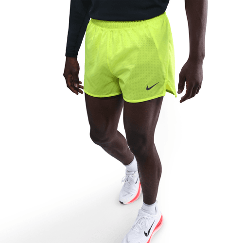 Person wearing bright yellow Nike shorts on a white background