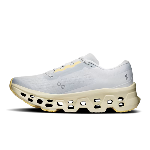 A single running shoe from the brand 'on' shown in a side profile view against a white background. The shoe features a light gray mesh upper, a thick cream-colored cushioned sole with black air pockets, and subtle pale yellow accents on the laces and toe cap.