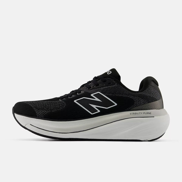 The mediail side of a NB 860 V15 black and white athletic shoe with red accents on a white background