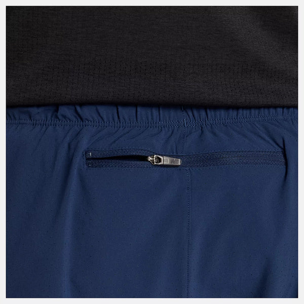 Close-up of navy blue pants with a zipper pocket, worn over black clothing.