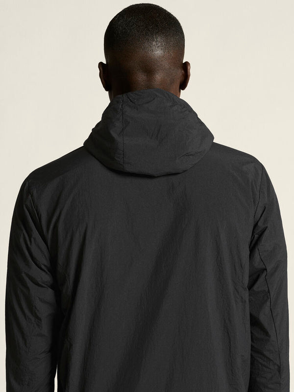Person wearing a black jacket with a hood on a plain background