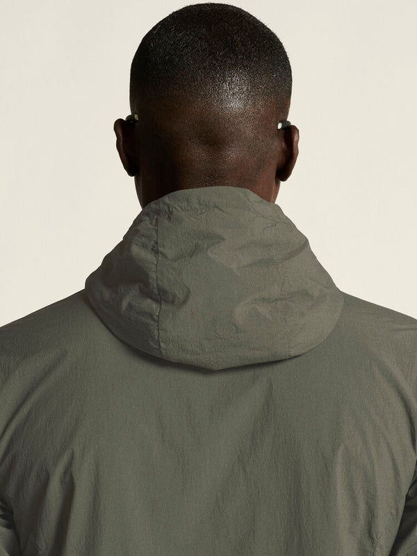 Person wearing a green jacket with a hood against a plain background