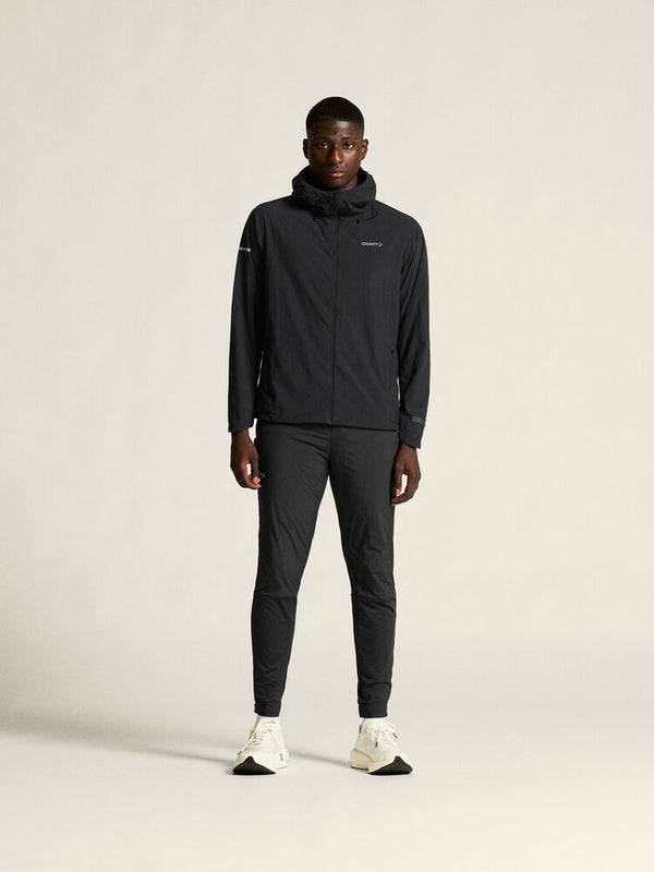Person wearing a black tracksuit on a light gray background
