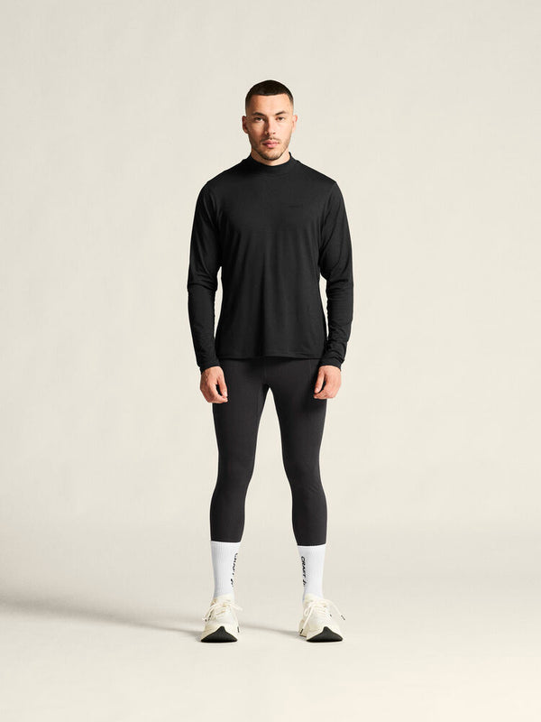 Man wearing a black long-sleeve top and leggings on a beige background