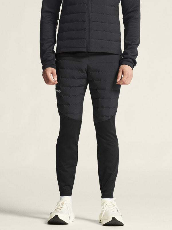 Person wearing a black puffer jacket and pants on a light background