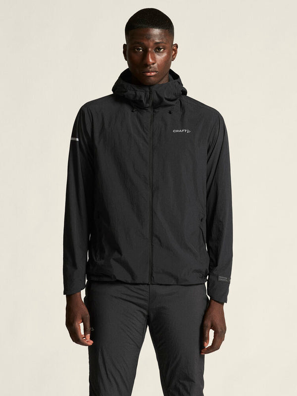 Person wearing a black jacket with a brand logo on a beige background