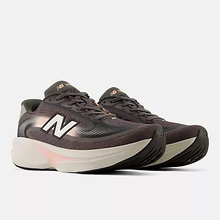 A pair of New Balance running shoes in dark brown and black with a white midsole and subtle pink accents, shown against a light gray background.