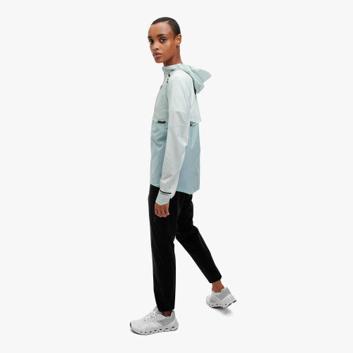 Side view of a model wearing the Women's Weather Jacket by ON in the color Surf/Sea
