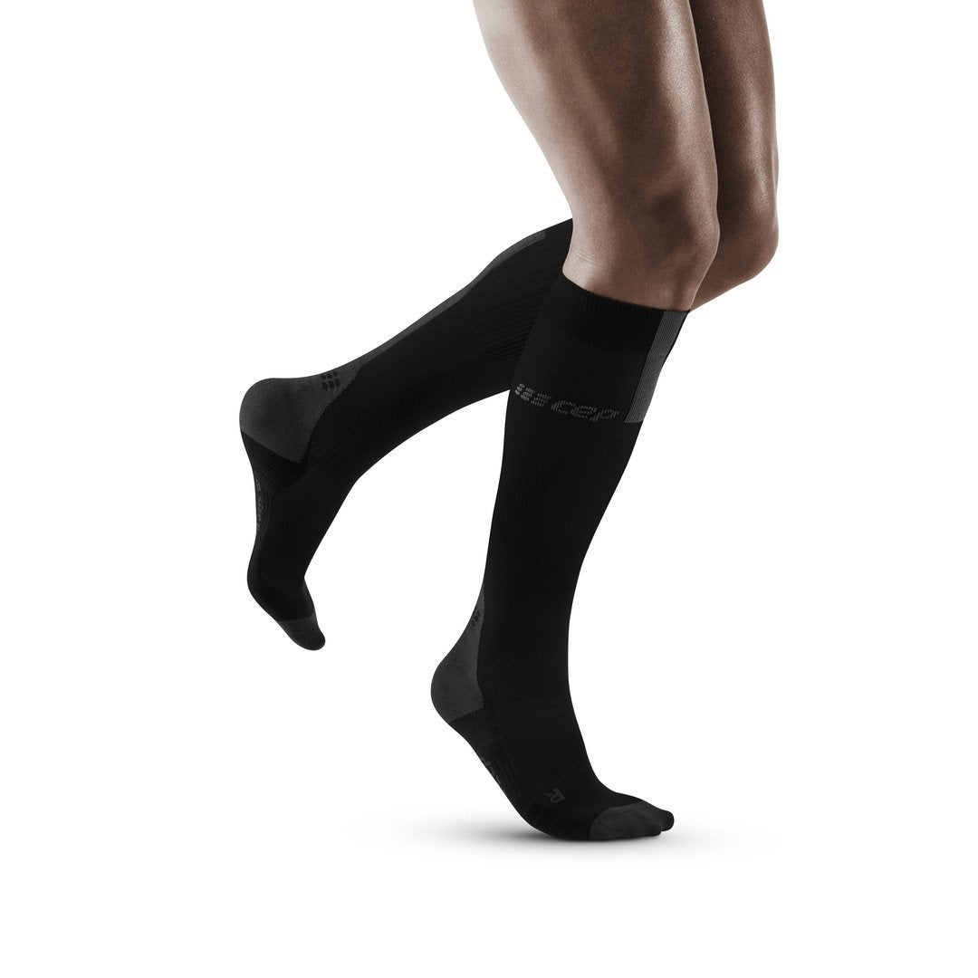 Right side view of a model wearing the CEP Tall Compression Socks in the color Black/Grey
