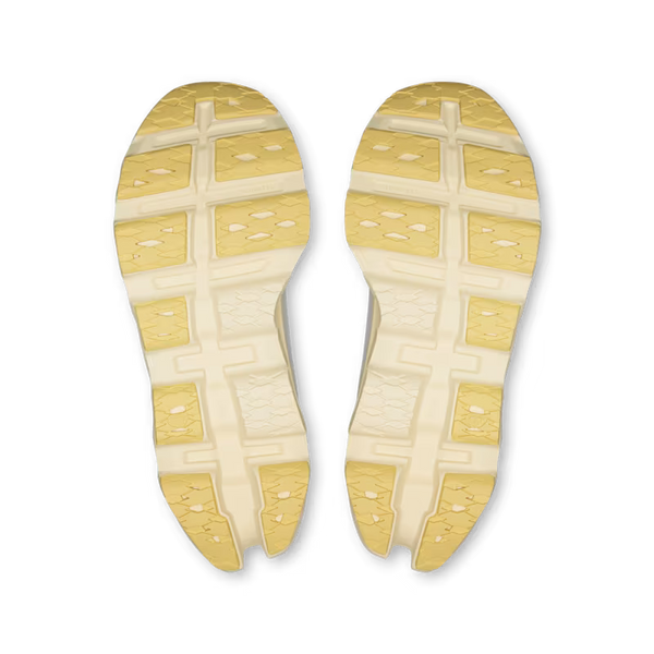 A pair of athletic shoe soles shown from the bottom, featuring a dual-tone design with pale yellow and off-white sections, photographed on a solid white background.