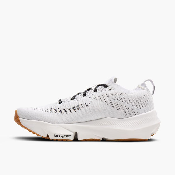 Medial side of a white athletic shoe with brown sole on a white background