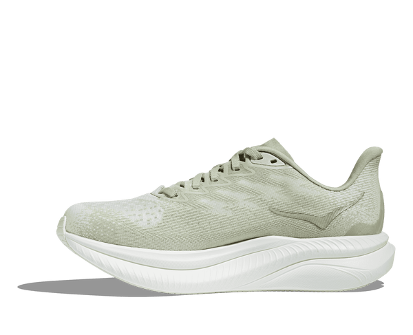 The Hoka logo is stitched near the ankle on the medial side of the upper in light green thread. 