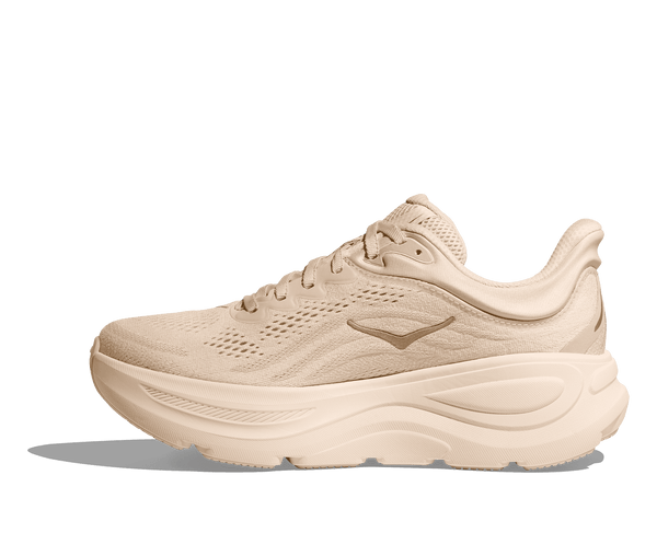 Medial side of a beige running shoe on a transparent background.