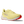Yellow running shoe with red sole on a green background