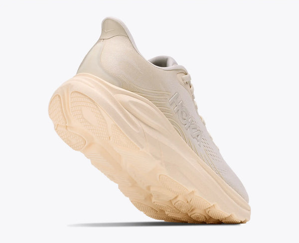 Beige running shoe with a white sole on a light gray background
