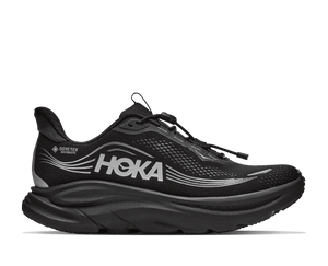 A black Hoka running shoe with a thick black sole, featuring a prominent silver HOKA logo and a small Gore-Tex Whisper label on the side, shown against a plain white background.